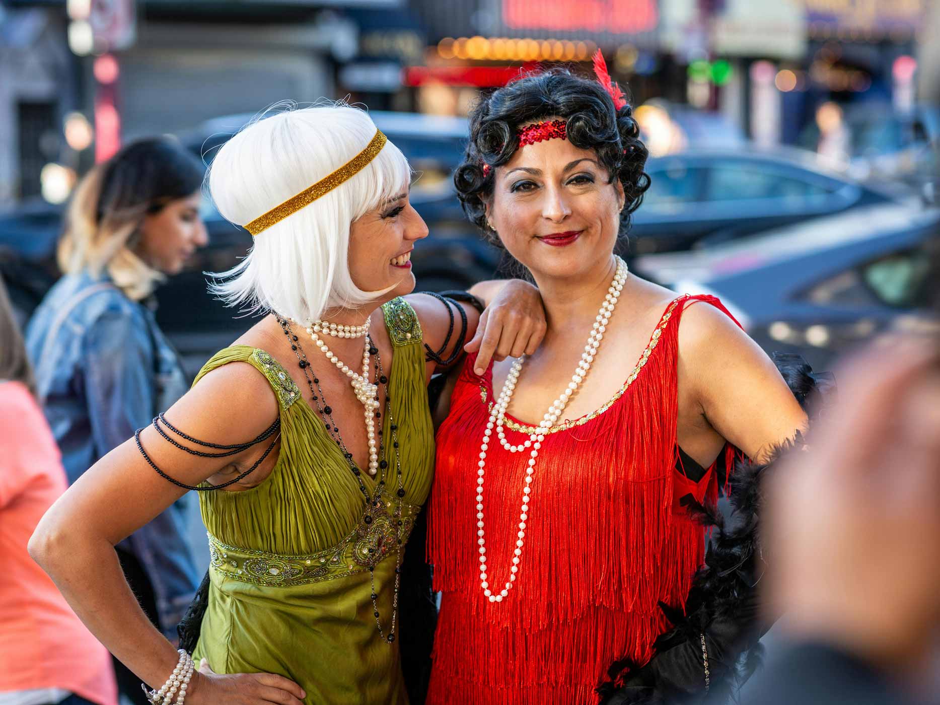 Zwei Frauen sind in bunten Kleidern im Look der 20er Jahre verkleidet und lachen