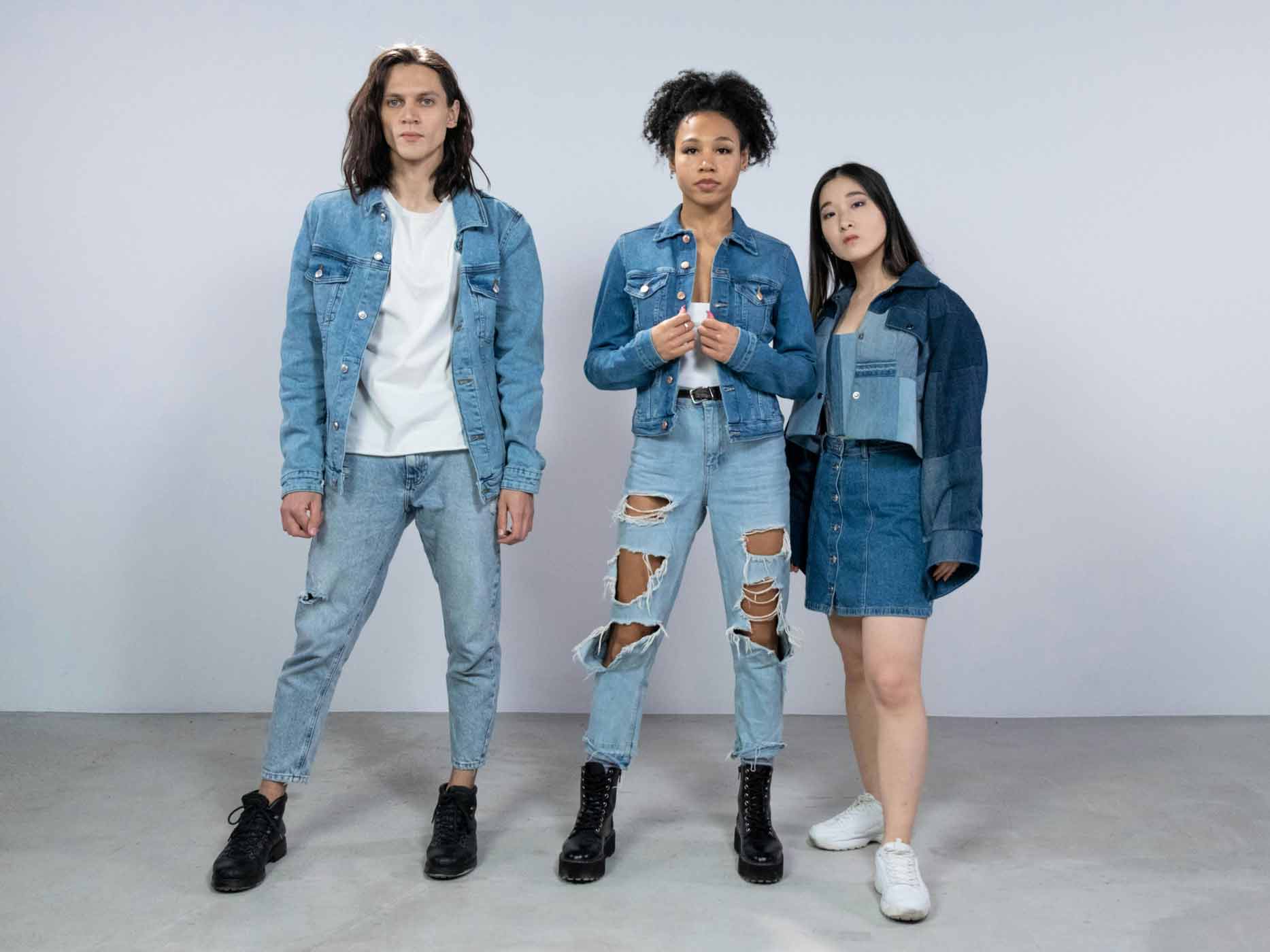 Ein Mann und zwei Frauen tragen verschiedene Outfits mit Jeansjacken