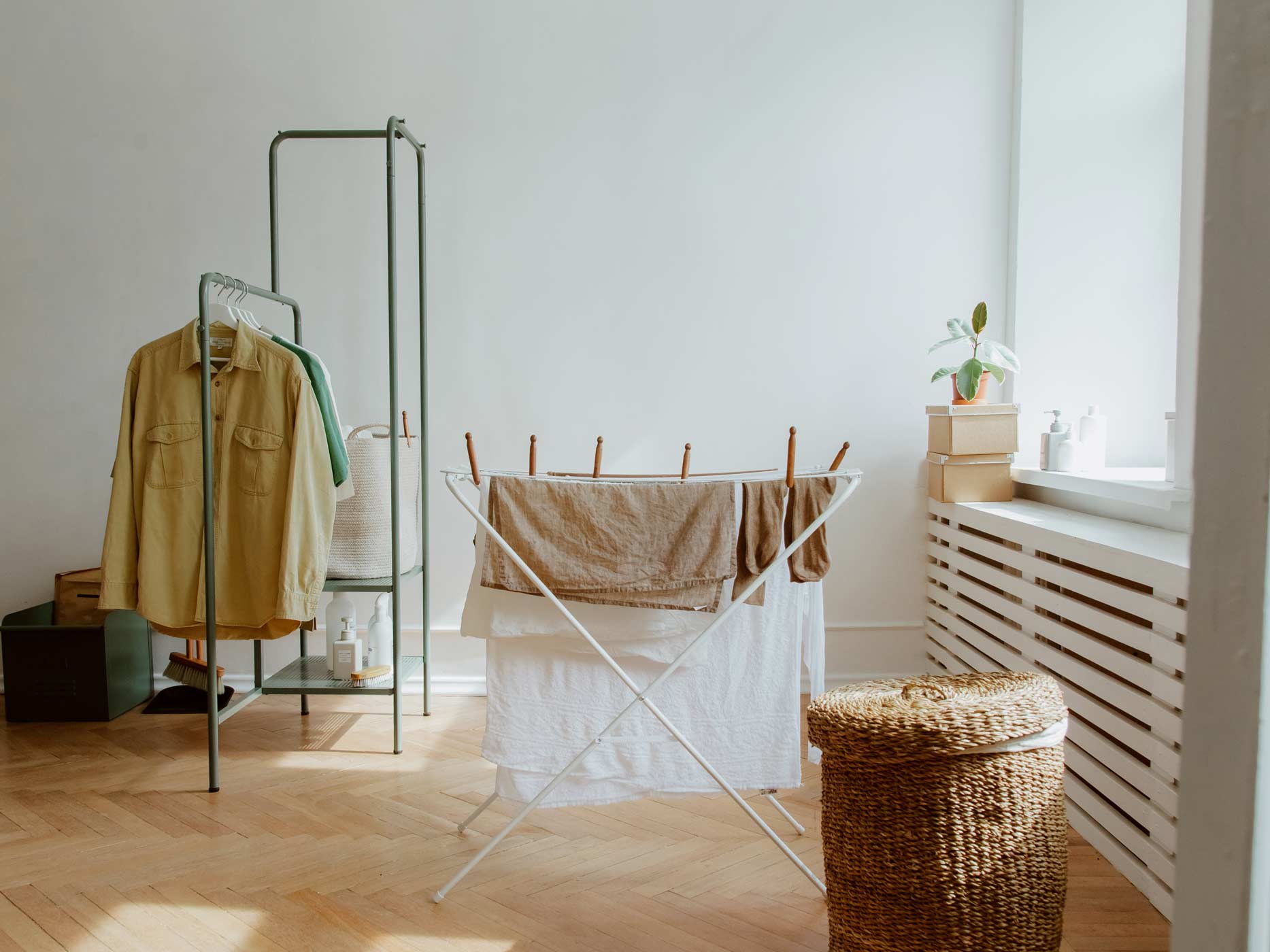 Hemden hängen rechts im Zimmer auf Kleiderbügeln und in der Mitte steht ein Wäscheständer mit Handtüchern, die mit Wäscheklammern befestigt sind