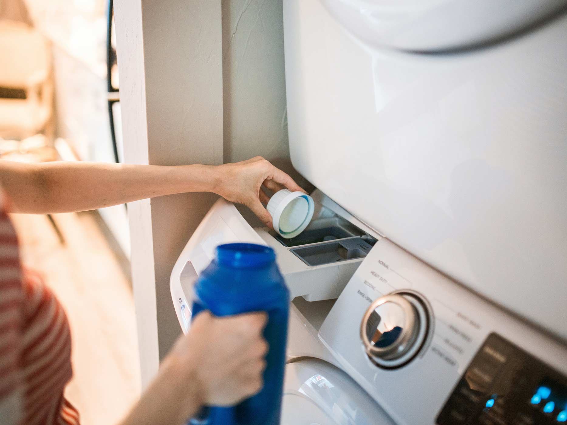 Frau kippt Waschmittel in den Behälter der Waschmaschine